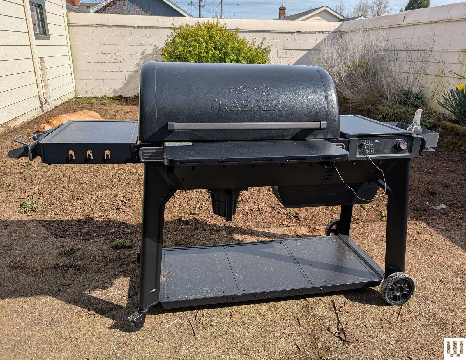 Front view of Traeger Woodridge Pro pellet smoker resting in a grassfree backyard with a white fence in the background